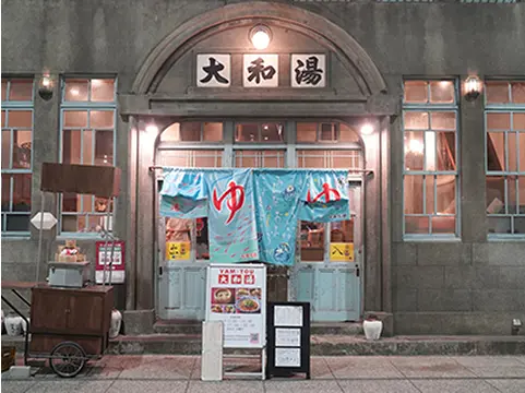 写真：大和湯ゆーゆーの入口。青色ののれんに「ゆ」と書いています